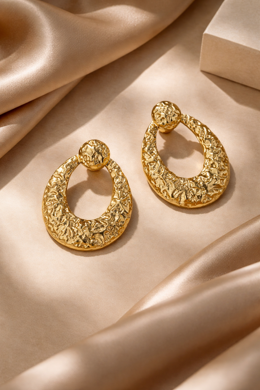 Gold hoop earrings on a beige fabric background